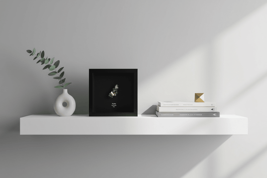 Pyrite cluster in decorative frame on a shelf